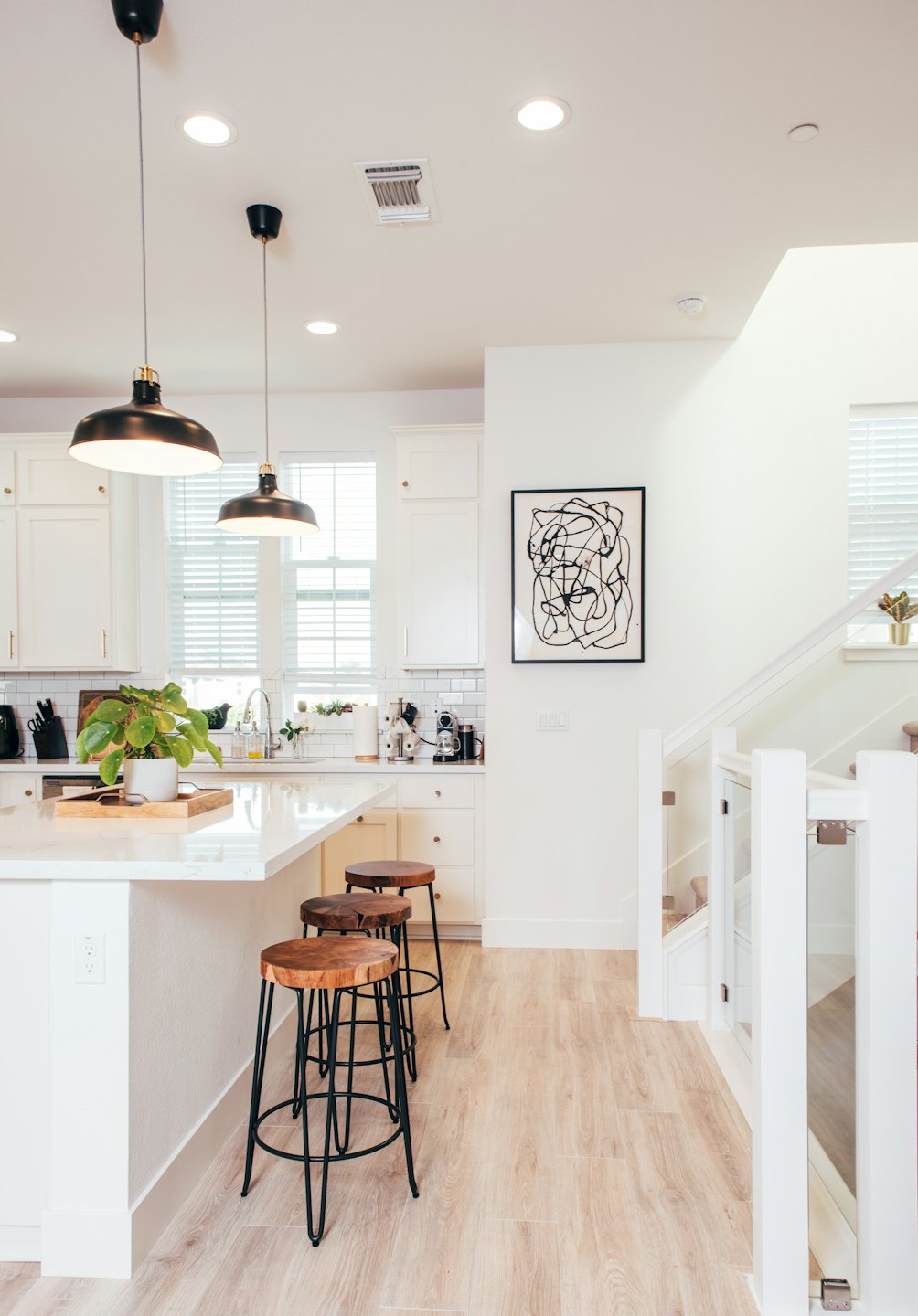 Modern kitchen island with bar stools and abstract art.