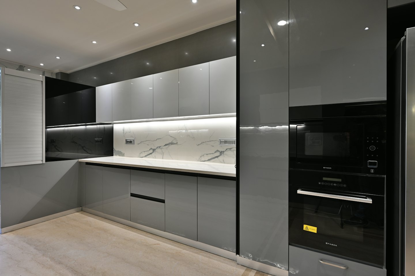 Modern grey kitchen with white marble backsplash and black appliances.