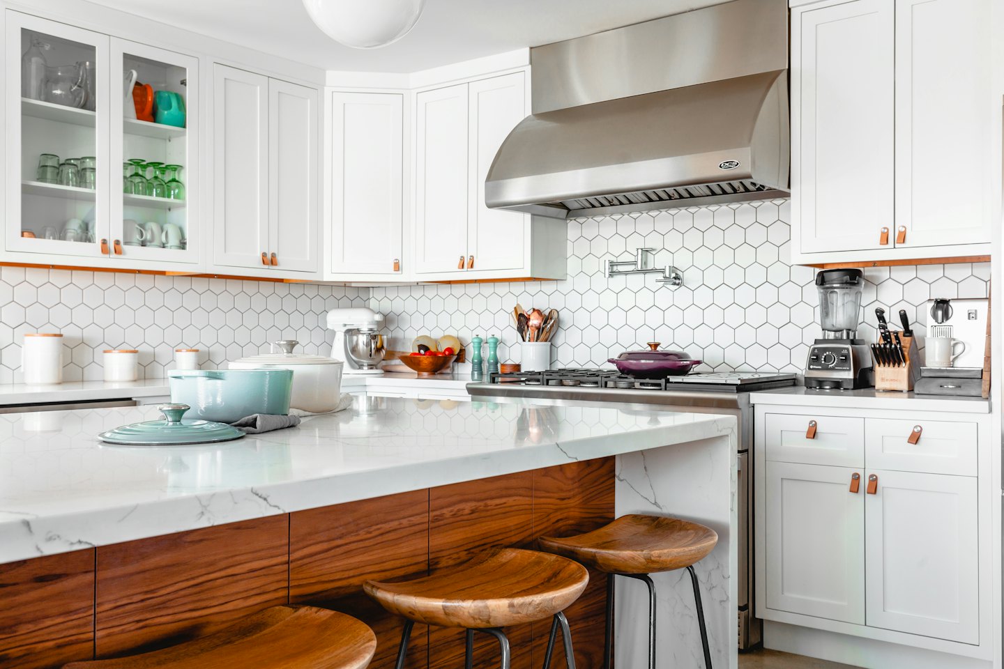 Modern kitchen with white cabinets and marble island.