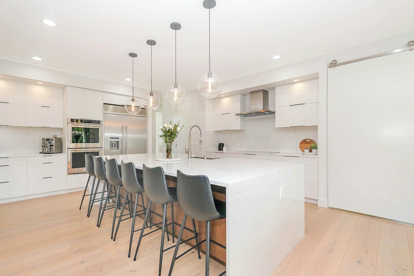 Contemporary kitchen with white cabinets and a marble island.